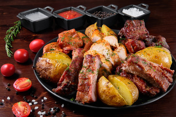 Assorted delicious grilled meat with vegetable. Mixed grilled bbq meat with vegetables. Set of shish kebabs or barbecue shashlik collection. Baked potatoes and fresh tomatoes. Various sauces for meat.