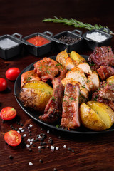 Assorted delicious grilled meat with vegetable. Mixed grilled bbq meat with vegetables. Set of shish kebabs or barbecue shashlik collection. Baked potatoes and fresh tomatoes. Various sauces for meat.
