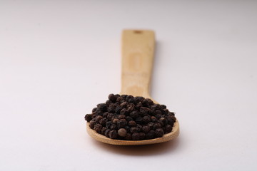 black pepper in wooden spoon isolated on white background.