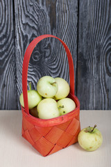 Apples in a red wicker basket. One lies nearby. Fruit harvest.