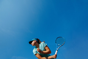 Low angle photo of girl playing tennis, holding racket backhand