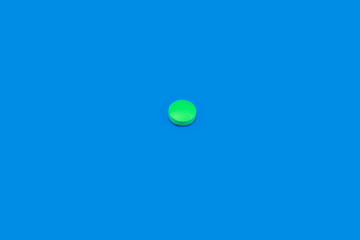 Green pill on blue background. Bright pill on indigo background. Blue seamless pattern and green pill.