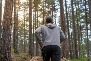 Man running in forest woods training and exercising for trail run marathon endurance race. Fitness healthy lifestyle concept with male athlete trail runner.