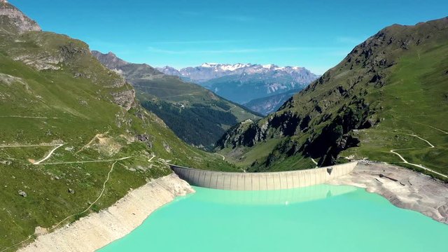 Aerial view with a drone over Moiry Dam in the middle of a valley. Renewable Energy and Electric Power technology scene. Beautiful landscape view in the background - Aerial 4k