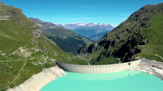 Aerial view with a drone over Moiry Dam in the middle of a valley. Renewable Energy and Electric Power technology scene. Beautiful landscape view in the background - Aerial 4k
