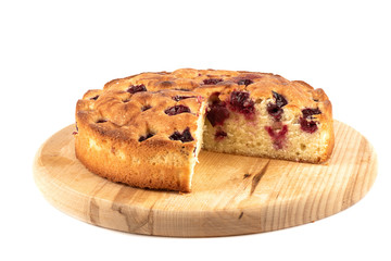 Cherry pie with triangular cut on a cutting board over white background.