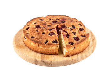 Cherry pie with cut triangular slice on a cutting board over white background.