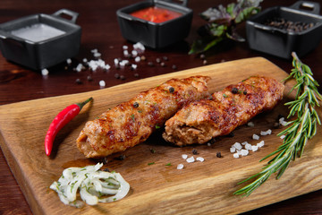 Chicken kebab appetizer with vegetables on a wooden board stand.