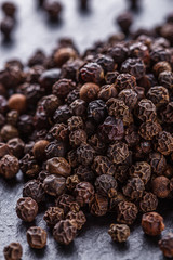 aromatic black pepper on a dark stone background
