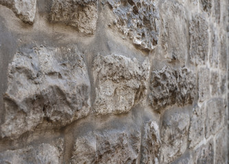 Ancient wall made of natural raw stone, perspective view, selective focus.
