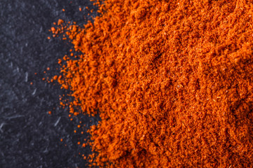 aromatic spicy chilli powder on a dark stone background