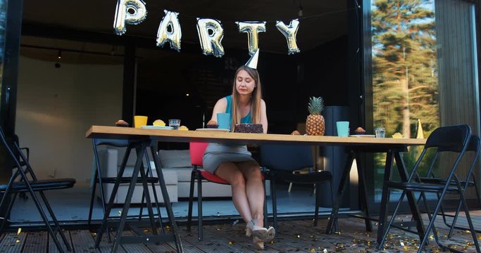 Lame birthday party on quarantine. Sad upset Caucasian young beautiful woman sits alone at home with cake slow motion.