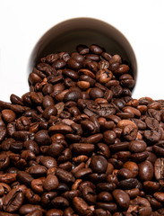 spilling coffee beans from a white cup