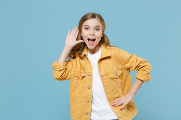 Excited little blonde kid girl 12-13 years old in yellow jacket posing isolated on blue background...