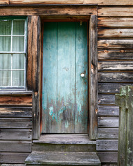 Old wooden blue door in an abandoned building with weathered wood siding