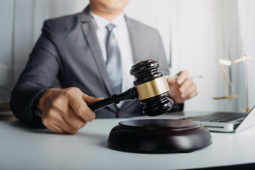 Justice and law concept.Male judge in a courtroom with the gavel, working with, computer and...