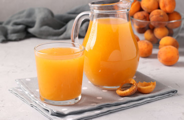 Obraz na płótnie Canvas Apricot juice with pulp in glass and jug on a gray background, Horizontal format, Closeup