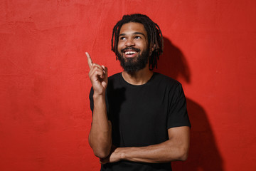 Smiling young african american man with dreadlocks 20s in black casual t-shirt posing pointing...