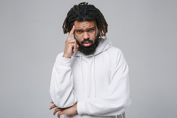 Dissatisfied puzzled young african american man with dreadlocks 20s wearing white casual streetwear hoodie posing put hand on head looking camera isolated on grey color background studio portrait.