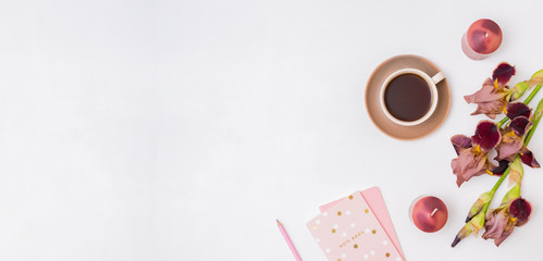 Flat lay composition with a cup of coffee and irises flowers on a white background