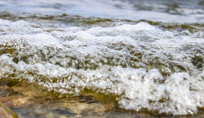Waves and Foam from the water on the rocks on the lake shore.