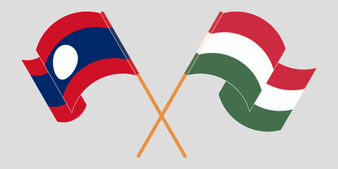 Crossed and waving flags of Laos and Hungary