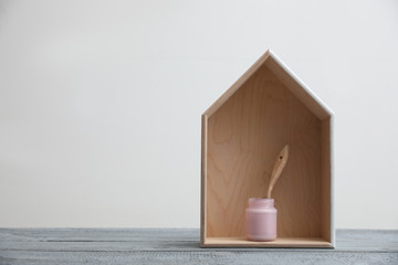 Brush with paint and wooden house model on grey table. Space for text