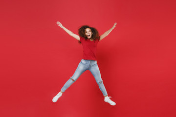 Fototapeta na wymiar Full length portrait of cheerful young african american girl in casual t-shirt isolated on red background studio portrait. People lifestyle concept. Mock up copy space. Jumping spreading hands legs.