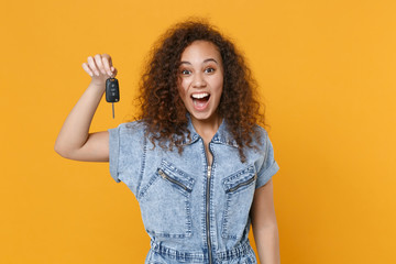 Surprised young african american girl in casual denim clothes posing isolated on yellow wall...