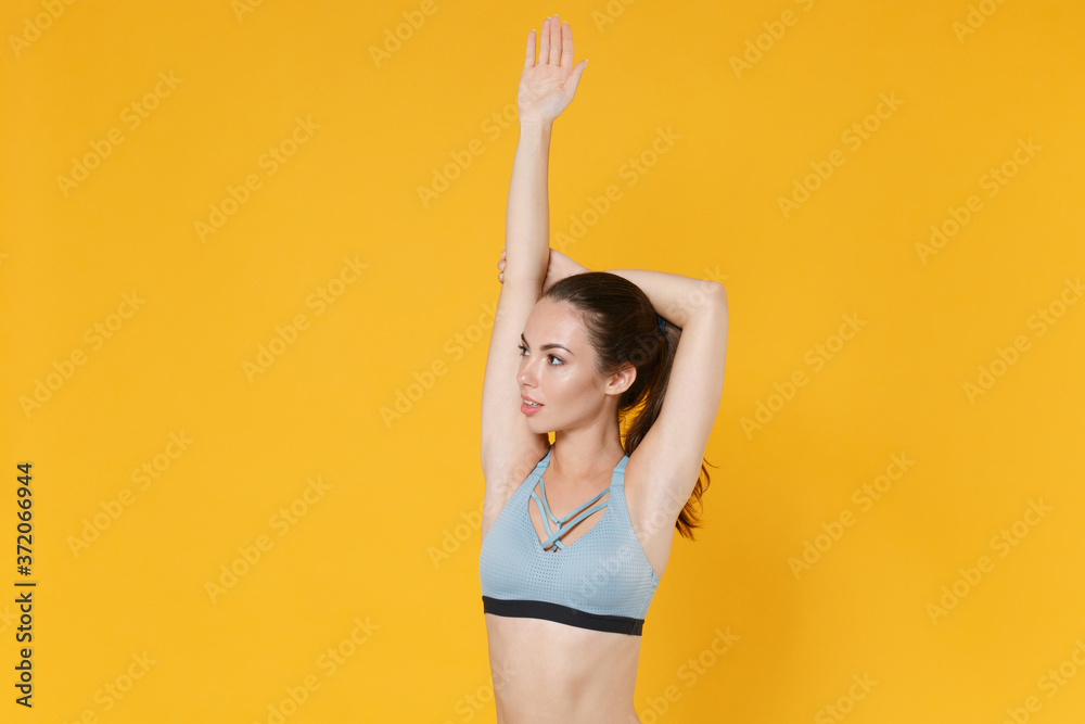 Wall mural Attractive young fitness sporty woman girl in sportswear posing working out isolated on yellow background studio. Workout sport motivation concept. Mock up copy space. Doing stretching exercising.