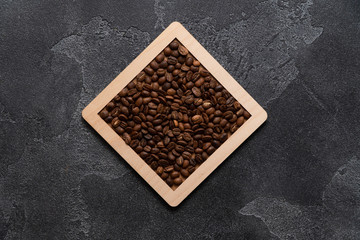 Coffee beans in wooden box on a dark surface.