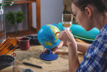 Woman is choosing a place for the next trip on the globe at the wooden table. Concept of travel and discovery
