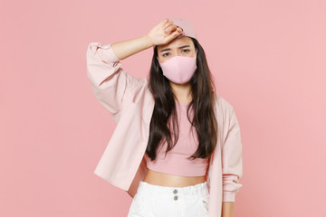 Exhausted sick young asian woman girl in casual clothes cap face mask isolated on pastel pink...