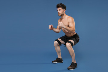 Full length portrait of young fitness sporty guy bare-chested muscular sportsman isolated on blue...