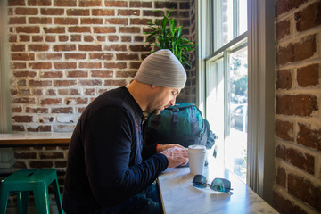 Man drinking coffee in a cafe in savanna georgia looking at his phone 