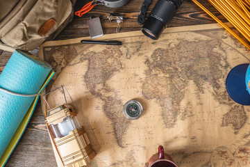 Hiking equipment for tourism and a map of the world with a globe on wooden table. Concept of travel...