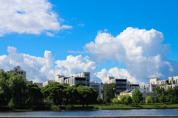 View of the river bank with houses against a blue sky with clouds. St. Petersburg.