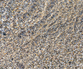 The sea pebbles are covered with the incoming wave.
