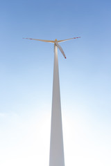 Fototapeta premium Wind turbine under blue sky in summer, renewable energy concept photo