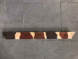 Stain sample applied on wood for furniture. A swatch wood color guide: shades of brown and samples of wood choice on dark background. Catalog samples in the carpentry workshop for designer to choose.