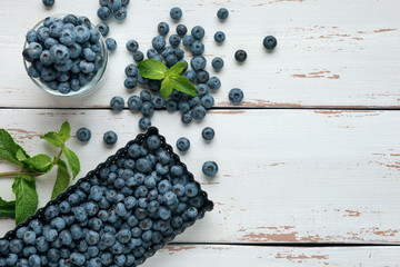 Glass jar of ripe blueberry with mint leaves on white Provence style wooden table. Flat lay. Copy space.