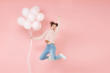Full length portrait happy young woman in casual sweater isolated on pastel pink background. Birthday holiday party people emotions concept. Celebrating hold air balloons jumping doing winner gesture.
