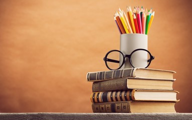 Stack of vintage books and colorful pencils on the desk