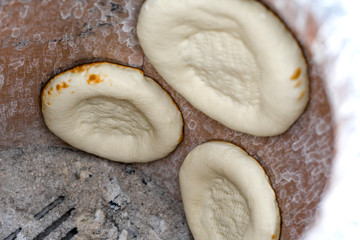 Lavash, flat unleavened white bread in the form of a thin flatbread made of wheat flour, is baked in the oven, in a tandoor. Pita bread in process. Close up view inside of tandoori oven. Shallow depth