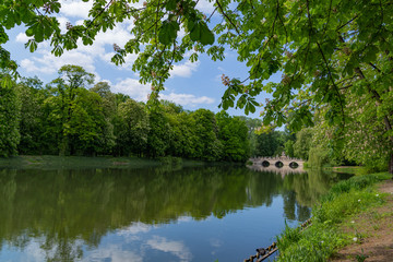 the bridge is reflected in the water across the lake in Royal Baths Park  is the largest park in Warsaw, Poland