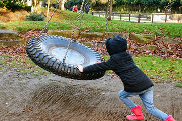 Little girl on swing in park.
