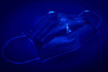 Medical mask under the black ultraviolet light to detect germ on the mask, UV light will show the hidden germ on the mask like glowing in the dark, sickness from covid 19 concept