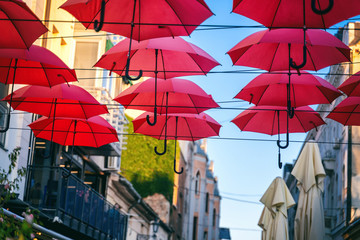Red umbrellas over street in european city, urban festive background and texture