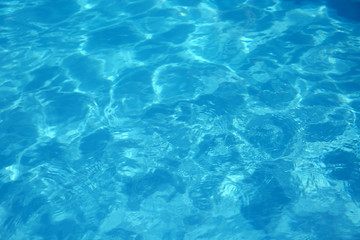Fototapeta na wymiar Texture of blue water in swimming pool as background, closeup