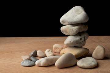 a bunch of smooth stones on a board on a black background